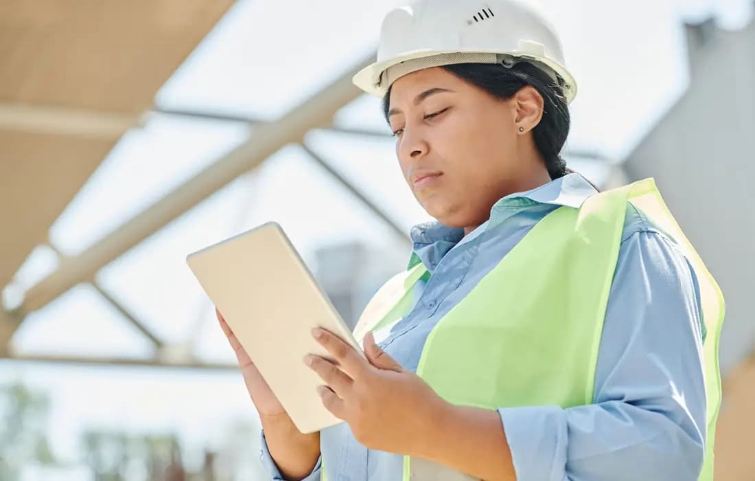 Site supervisor using tablet to manage construction equipment allocation and site updates