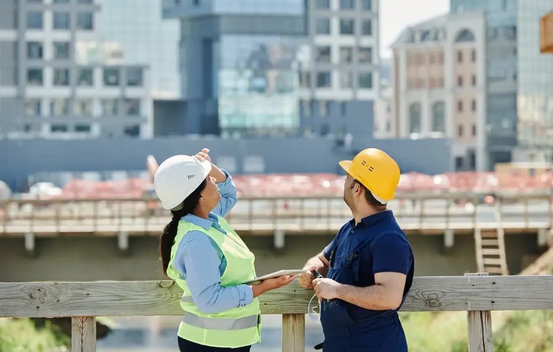 Construction managers using tablet and walkie talkie for project coordination software